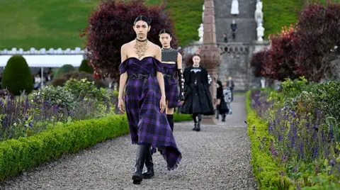 Reuters Models dressed in tartan dresses and wellington boots. They are walking along a garden path - like a catwalk - at a Scottish castle. 