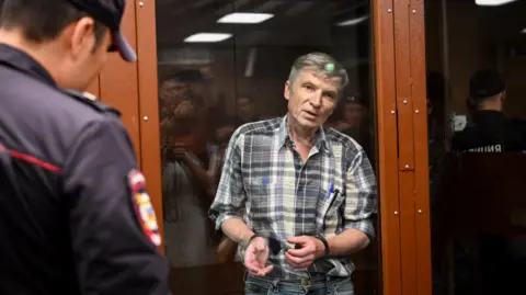 Getty Images Moscow city deputy Alexei Gorinov stands inside a glass cell during the verdict hearing in his trial at a courthouse in Moscow in July 2022