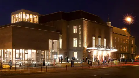 An artist's impression of what an updated Watford Colosseum, an entertainment building, in Watford, could look like. It shows a large brick building with people outside, signage and lights. 