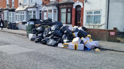 A pile of bin bags and boxes on the street