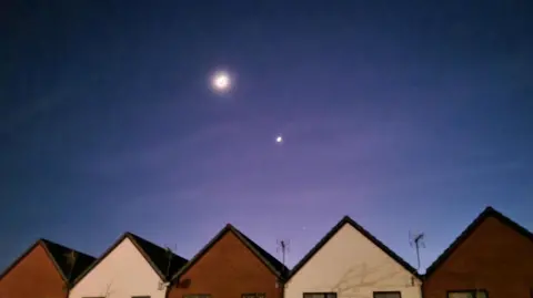 Lizzy Weather Watchers A row of houses with a crescent Moon and Venus visible above them