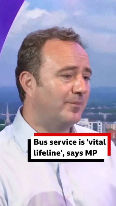 Danny Chambers sits in the BBC Radio Solent studio, he looks slightly away from the camera and has short light brown hair and wears a white collared shirt.