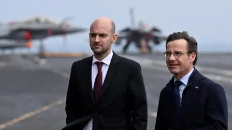 TT/Reuters Two men stand on a ship in suits and ties