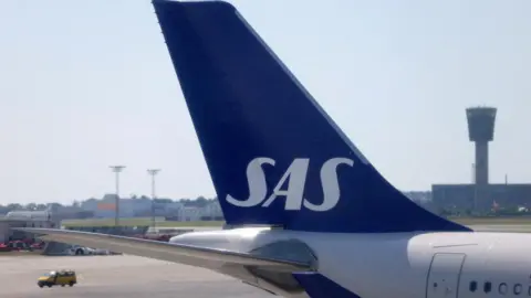 The tail fin of a parked Scandinavian Airlines (SAS) airplane is seen on the tarmac at Copenhagen Airport in July 2022