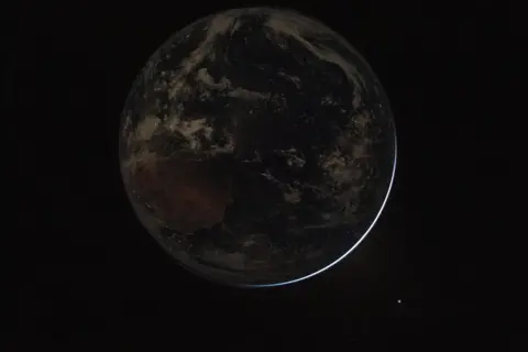 NASA/Reid Wiseman Lights twinkle in the nighttime as the Earth completely occludes the Sun in this image taken from the Orion space capsule.