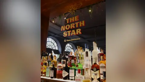 Team Domenica The interior of The North Star pub next to the Royal Pavilion in Brighton, East Sussex. 'The North Star' has been engraved into the mirror above the bar, where a number of alcoholic spirits are visible. 