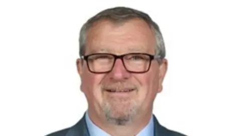 Staffordshire County Council Peter Mason, a man with a short grey beard and wearing glasses, is pictured against a white background.