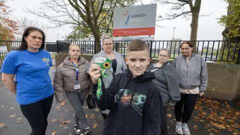 A picture of student Finlay and some parents outside Werneth School on Harrytown road in Stockport