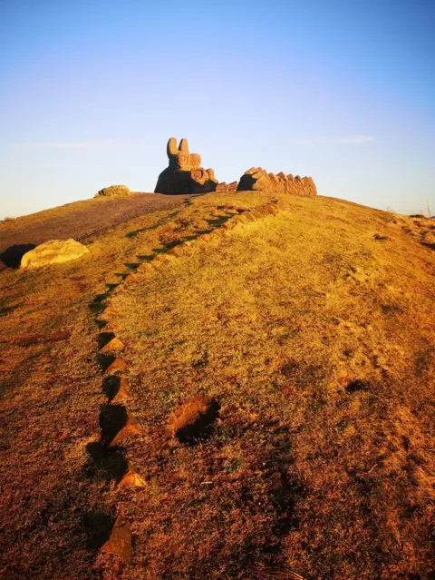 Julie Nelis A dragon statue on the top of a hill cuts a clear figure in the last sunlight of a cold but clear winter day