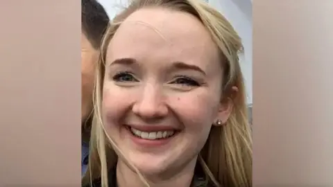 ANDREA BRADY A close-up photo of Jessica Brady who is smiling broadly and looking directly at the camera, with long blonde hair, brown eyes and a visible earing in her left ear.