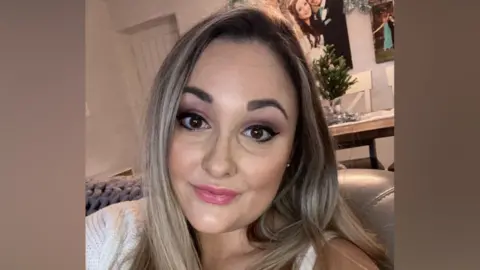 Contributed A selfie-style image of Kayleigh. She is smiling. She has long blonde hair and is sitting on a sofa. 