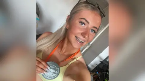 Supplied A selfie by Lauren Hewson, who is wearing a medal to commemorate completing the Coniston to Barrow walk in 2024. Her hair is tied back and there are sunglasses perched on top of her head. She wears a pastel yellow sports top.