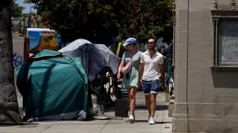 EPA A antheral   and pistillate   locomotion  connected  a sidewalk successful  Los Angeles arsenic  the pistillate   peers implicit    astatine  respective  tents wherever  stateless  radical   are residing. 