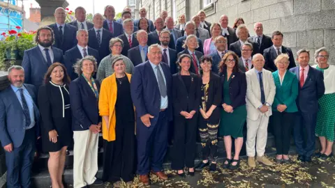 BBC Les États de Guernesey, aux côtés de fonctionnaires des officiers de justice debout sur les marches à l'extérieur de la Cour royale. 