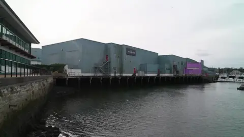 A blue building in front of a harbour on a cloudy day