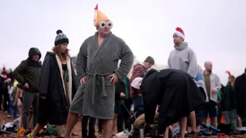 Reuters A man wearing a turkey themed hat prepares to participate in a Christmas Day dip on Brighton beach in southern England, December 25, 2024.