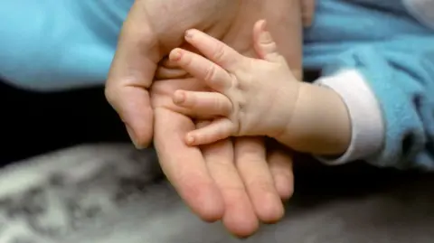 Getty Images A picture of a baby's hand in an adults hand 