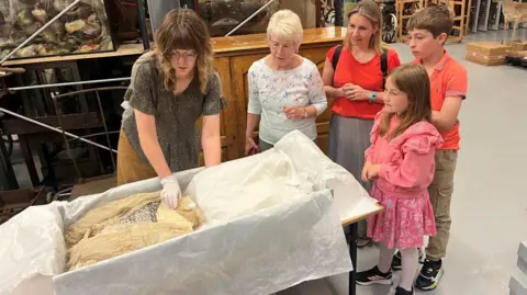 Leeds Museums and Galleries Jennifer Slater with daughter Christina Bromley and Lily's great-great-grandson Alexander and great-great-granddaughter Emmeline look at the wedding dress