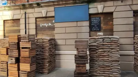 Paul Schofield A building in Hull's Old Town has been obscured by sandbags, wooden crates and boarded up windows as part of a film set.