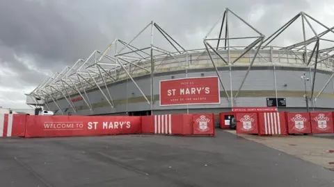 A wide image of St Mary's football stadium with Southampton football club branding surrounding it and wording saying "welcome to st mary's"