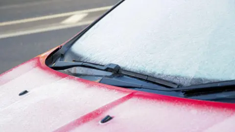 A red car with an icy windscreen.