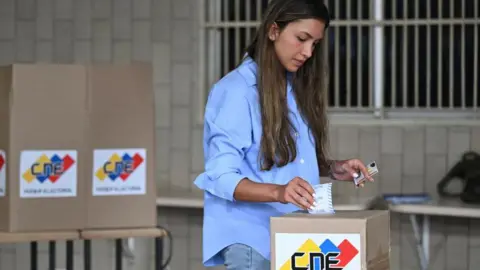 Getty Images A woman casts her vote in Caracas, 28 July 2024