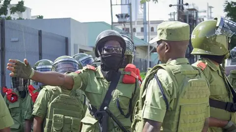 Tanzania police officers, in jungle green uniform, and helmets