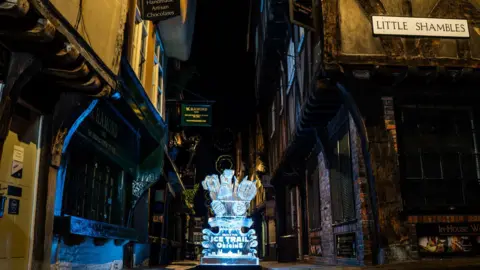 Daniel Easton View of the Shambles with tudor-framed buildings with a sign on the right hand side stating Little Shambles, with an ice sculputre in the centre of the street