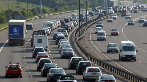 PA Media Heavy traffic on a three-lane motorway, which bends around to the right.