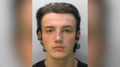 A mugshot of a man with medium length black hair.