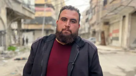 Aamir Peerzada/BBC Abdul Rahman Hijazi stands in the middle of the road, looking directly into the camera