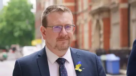 PA Media Andrew Gwynne wearing a suit.