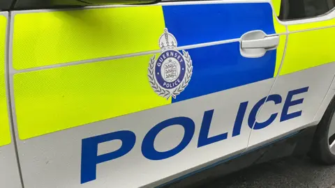 Side of car with yellow and blue with Guernsey Police logo and word POLICE 