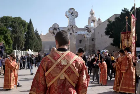 Getty Images Umat ​​beriman dan pemimpin agama menghadiri upacara tersebut saat Patriark Theophilos III dari Yerusalem memimpin hari perayaan Natal Ortodoks di Gereja Kelahiran, yang diyakini sebagai tempat kelahiran Yesus Kristus, di Betlehem, Tepi Barat, pada 06 Januari 2025 .