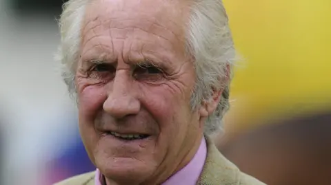 Getty Images Bill Turner. He is an older man with white short hair. He is squinting and his mouth is open slightly. The collar of his pink shirt is visible and he is wearing a light coloured jacket over the top. 