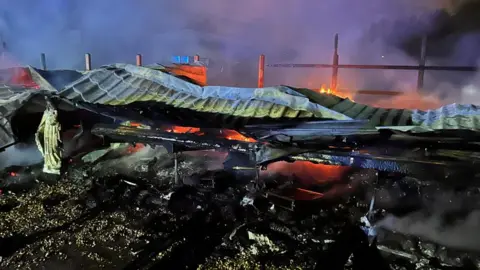 Essex Fire and Rescue Service The gutted remains of the caravans after the fire was brough under control. All that remains is the collapsed roof and there are still some pockets of fire visible underneath.