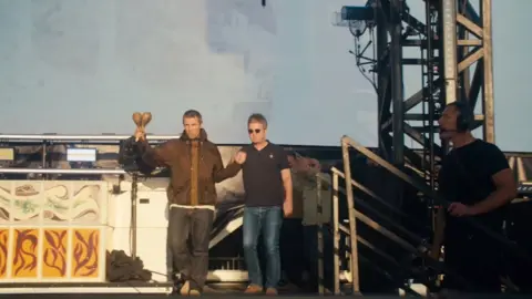 Liam and Noel Gallagher walk out on stage hand in hand