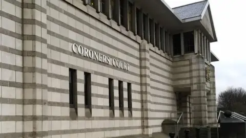 An image of the exterior of Doncaster Coroner's Court. It has stonework with horizontal stripes, and a crest above the entrance