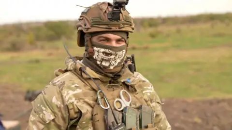 BBC/Maarten Lernout Gunner Alex dressed in camouflage