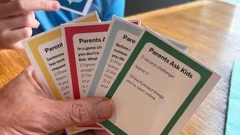 A picture of someone holding four cards up. They are red, green, yellow and blue in colour.
