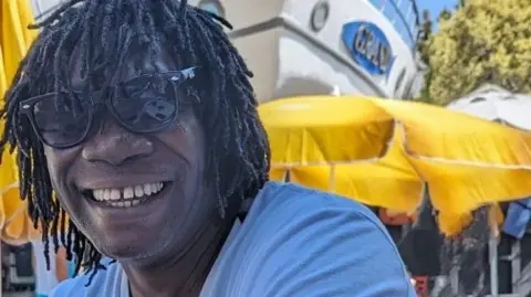 Met Police/Family Handout Image of Derek Thomas, a man with dark dreadlocks wearing a blue t-shirt and sunglasses