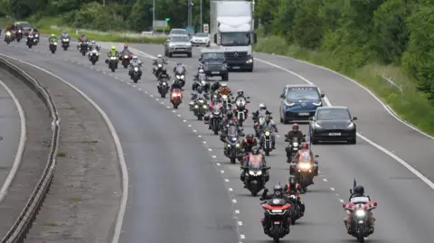 PA Media Dozens of bikers travelling in a procession along a motorway as part of Dave Day.