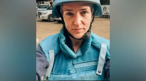 Victoria looks to camera whilst wearing a protective blue jacket and blue helmet 