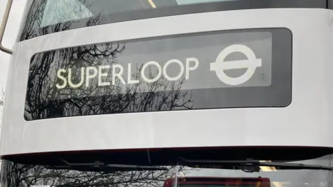 A close up of the Superloop sign on the front of a London bus. The London Transport roundel is also visible. 