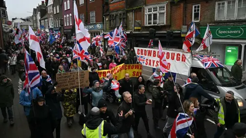 Getty A large group of people protesting wave England flags and union jacks. Signs read "Crowborough says no"