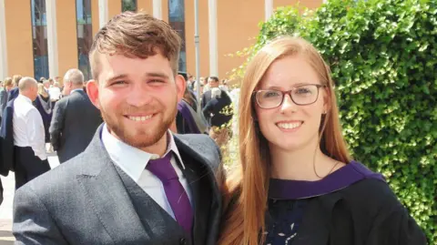 Nikita Goddard James Nunan and Nikita Goddard dressed smartly at Goddard's graduation ceremony. They are smiling and behind them is a large crowd of people.