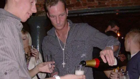 UGC Adam Minett, in a photo taken in the mid-2000s, pours champagne out of a bottle while on a night out in a Liverpool nightclub