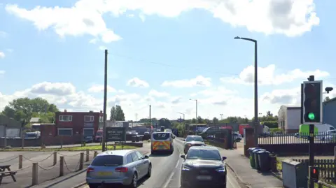 Station Road in Rowley Regis has buildings on either side and vehicles can be seen driving down it