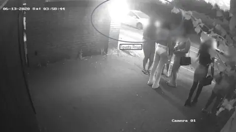 Essex Police Young women standing in the dark as seen on CCTV. A Toyota Prius is highlighted driving past