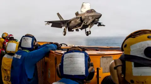 US service members aboard the USS Boxer amphibious assault ship watch a US fighter jet in flight. File photo